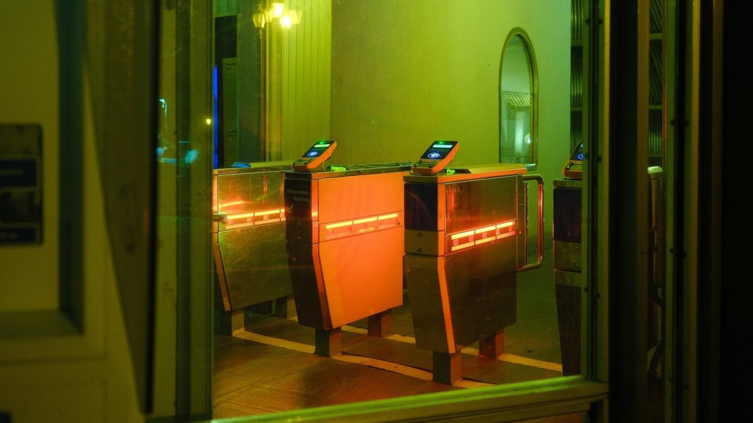 Entrance turnstiles illuminated with orange and green lights.