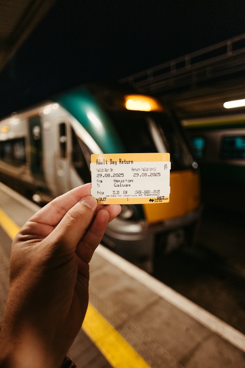 Hand holding train ticket with train in background.